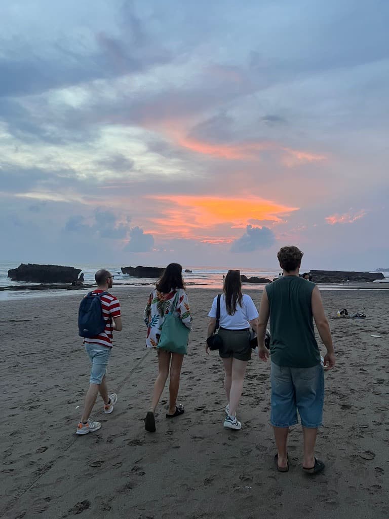 Four students walking together along a Bali beach at sunset