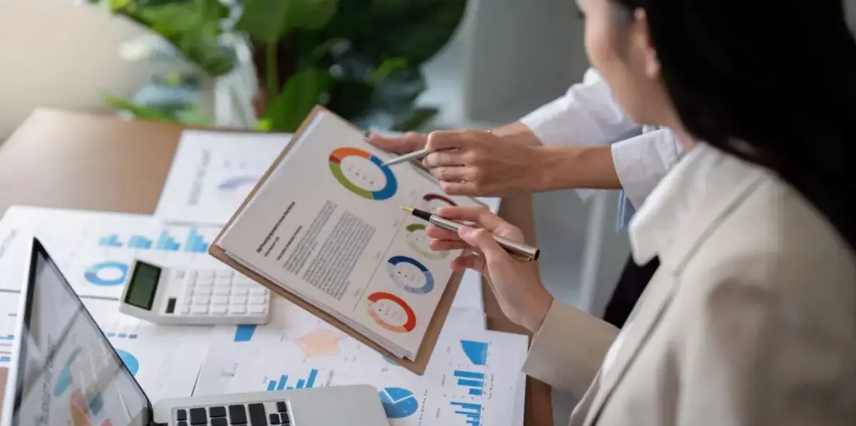Two people reviewing market-research charts and reports