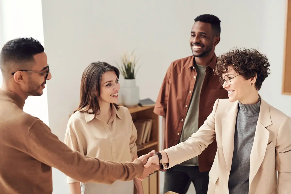 Business partners shaking hands while their team looks on