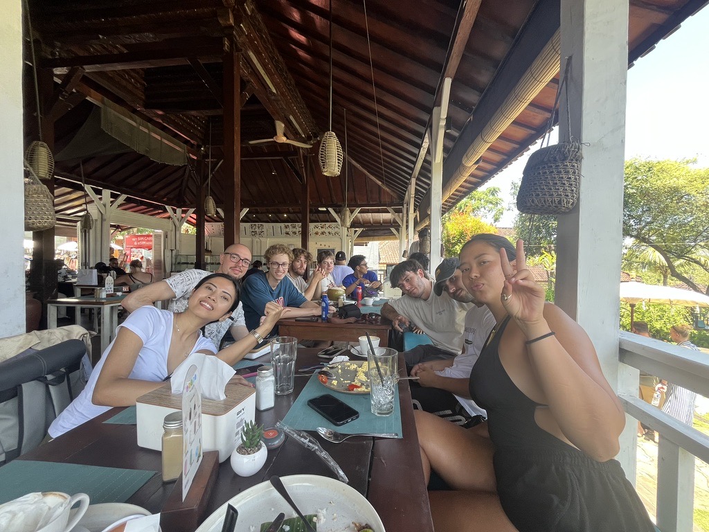 Students sharing breakfast around a long table at an open-air warung in Bali