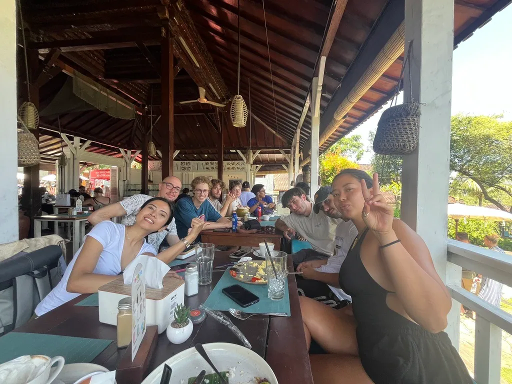 Students sharing breakfast around a long table at an open-air warung in Bali