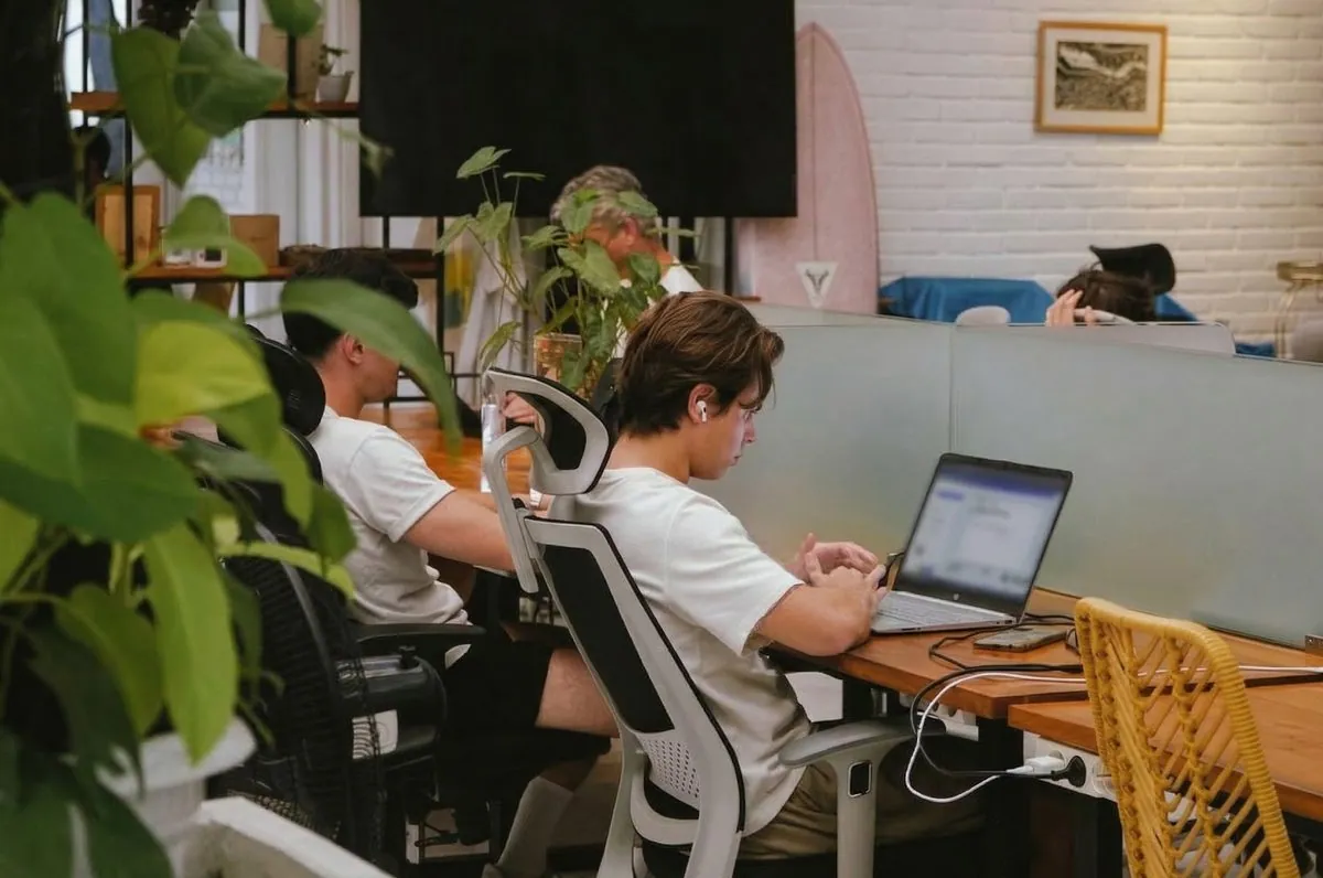 An intern working heads-down at a laptop inside a Bali coworking placement