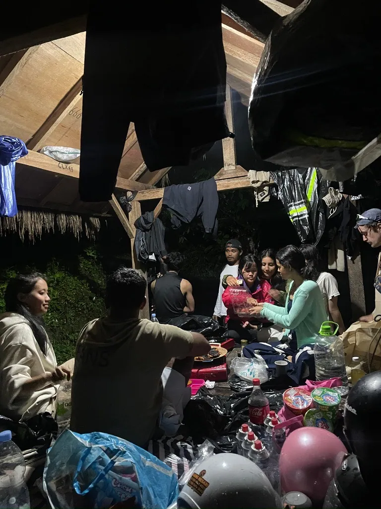 Interns cooking a shared meal on portable gas burners at a mountain camp in Bali