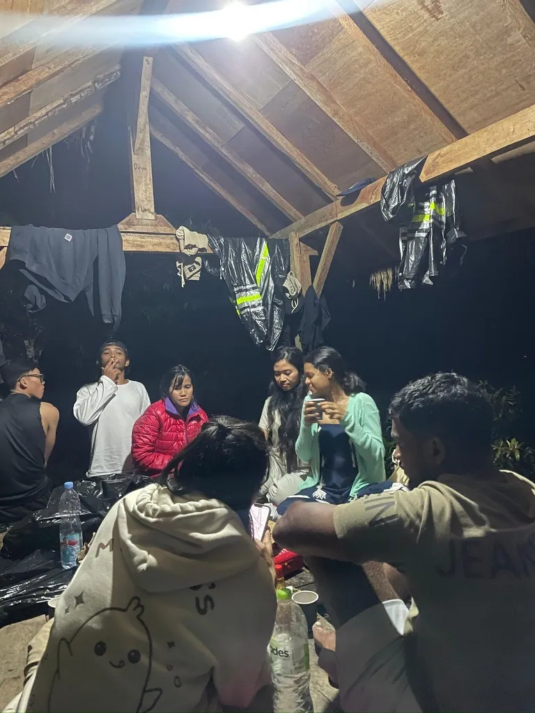 Interns sheltering under a wooden hut on Mount Batur with wet clothes hung up to dry