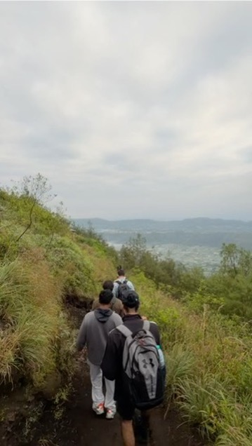 A group of interns walking together in single file down a mountain trail in Bali
