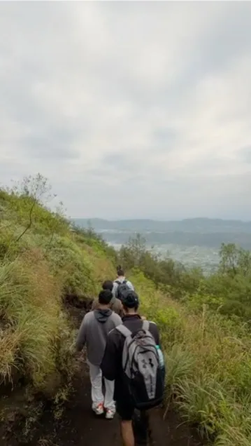 A group of interns walking together in single file down a mountain trail in Bali